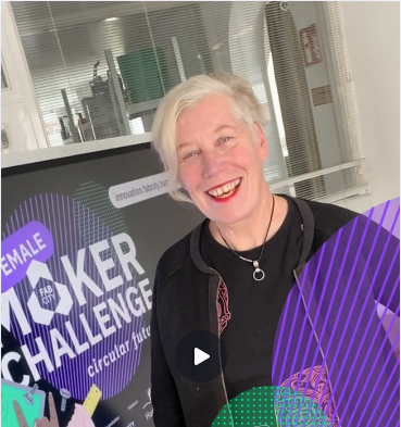 Eine lächelnde Frau mit kurzen hellen Haaren steht vor einem Plakat der "Female Maker Challenge" von Fab City Hamburg.