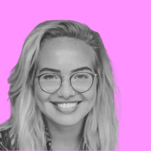 Porträt von Alina Schukov, einer lächelnden Frau mit Brille und langen Haaren, vor einem pinken Hintergrund.