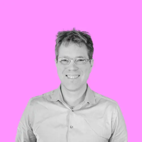 Schwarz-weiß Porträt von Axel Sylvester, einem lächelnden Mann mit Brille und Hemd vor einem pinkfarbenen Hintergrund, auf der Seite von Fab City Hamburg.