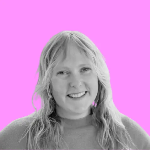 Porträt von Liesa Balzer, einer lächelnden Frau mit langen, hellen Haaren, in Graustufen vor einem leuchtend pinken Hintergrund.