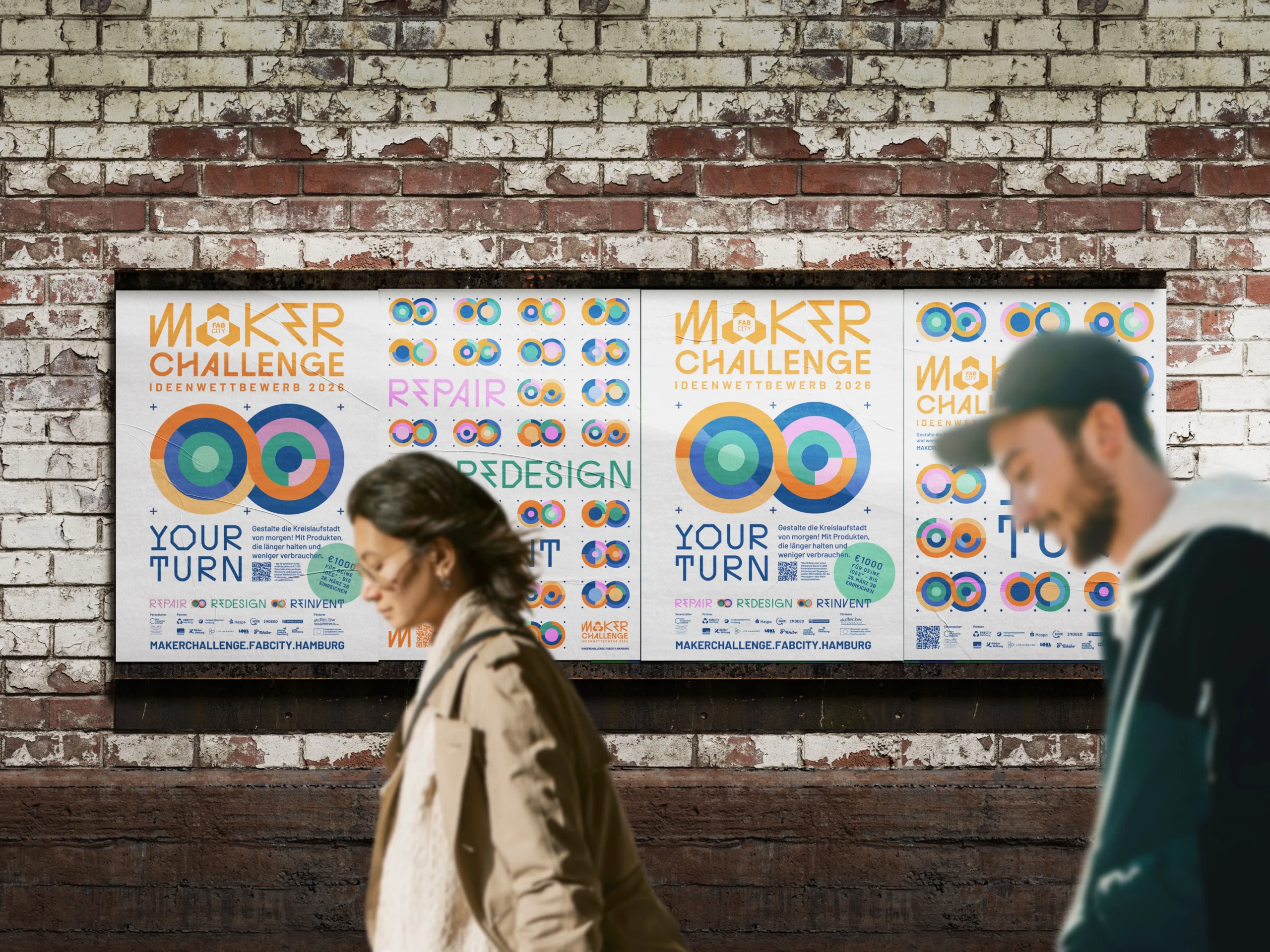 Drei Plakate für den Fab City Maker Challenge Ideenwettbewerb 2026 hängen an einer Ziegelwand, während zwei Personen unscharf vorbeigehen.